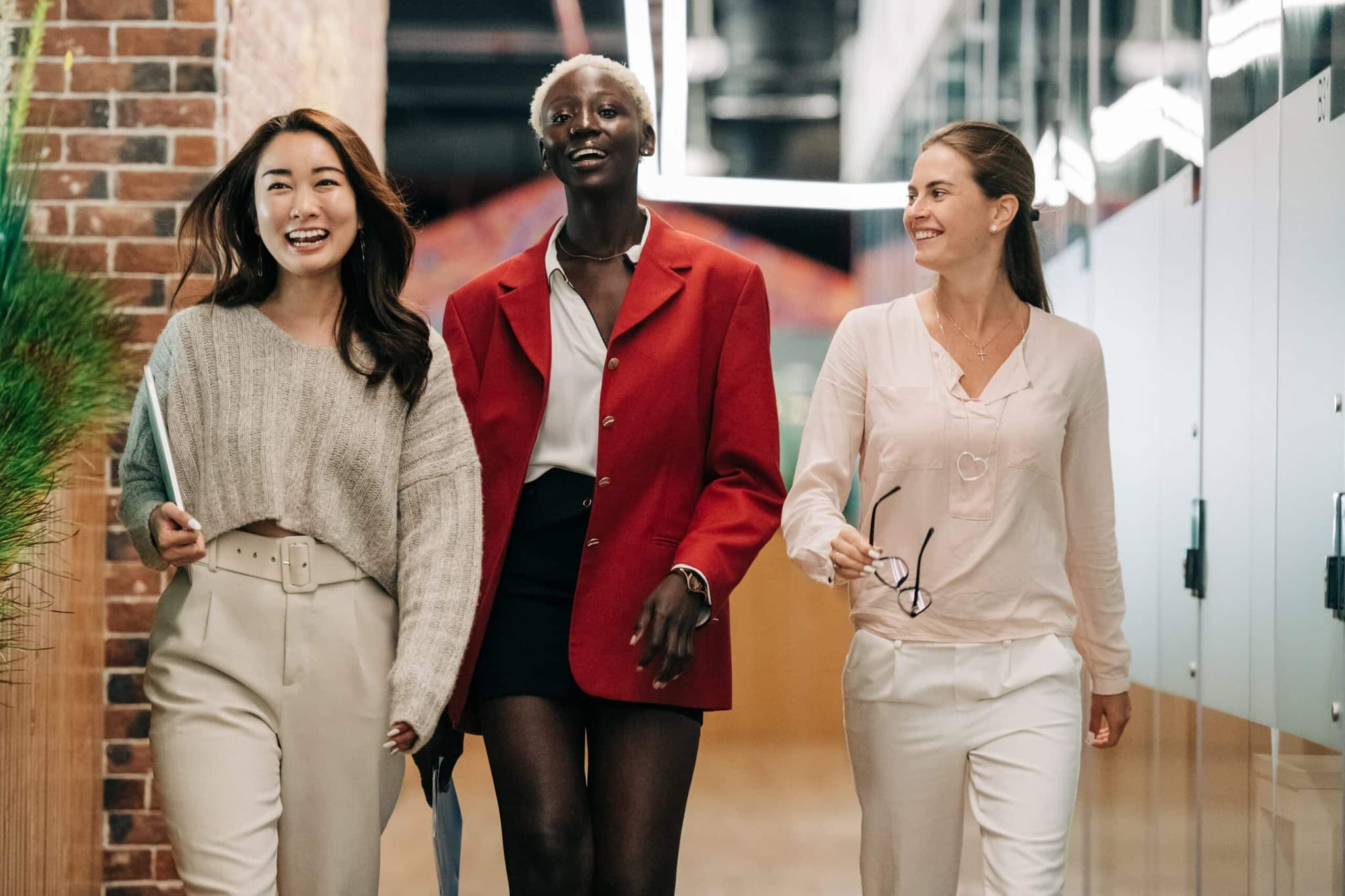 Three woman walking together, smiling as they enjoy each other's company. They appear to be carefree and happy.
