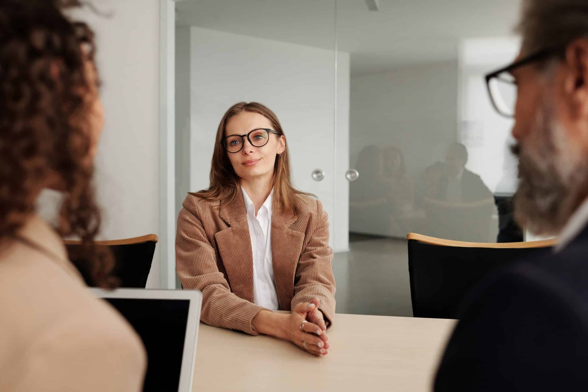 A girl is smiling while doing an interview. We can see her facing the interviewers, but only the backs of their heads are visible