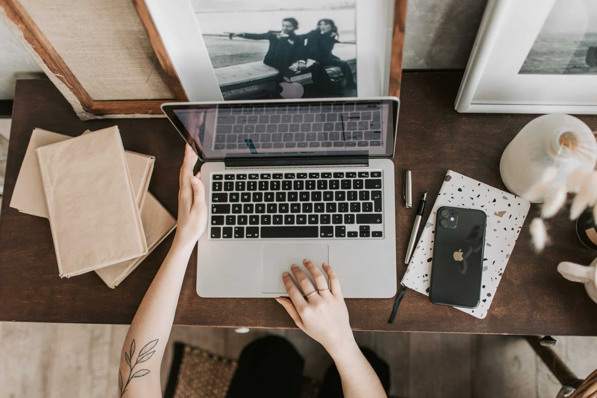 A laptop placed on a table among other items, including papers and a picture frame.