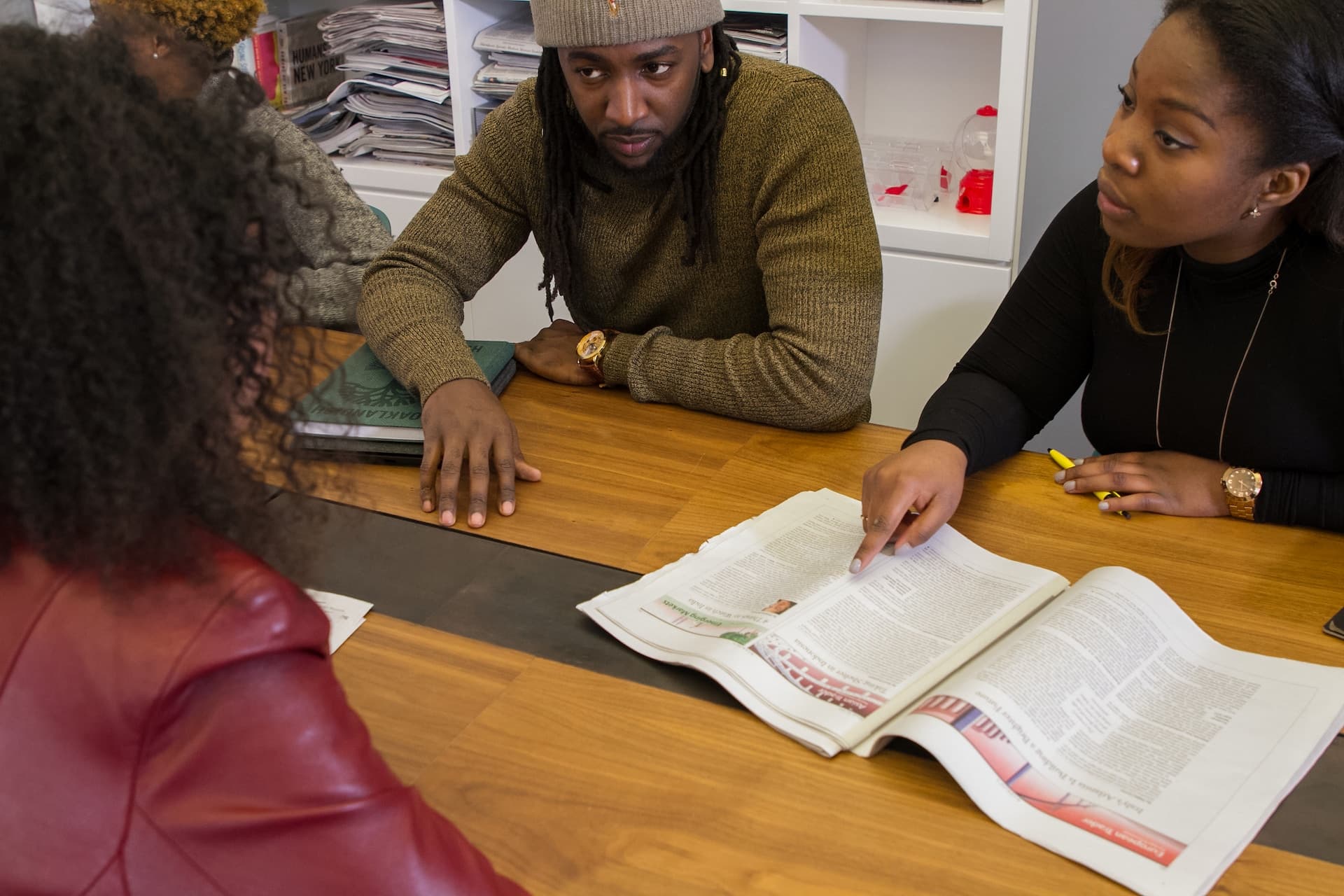 Three people engaged in a discussion, with one person pointing to a paper.
