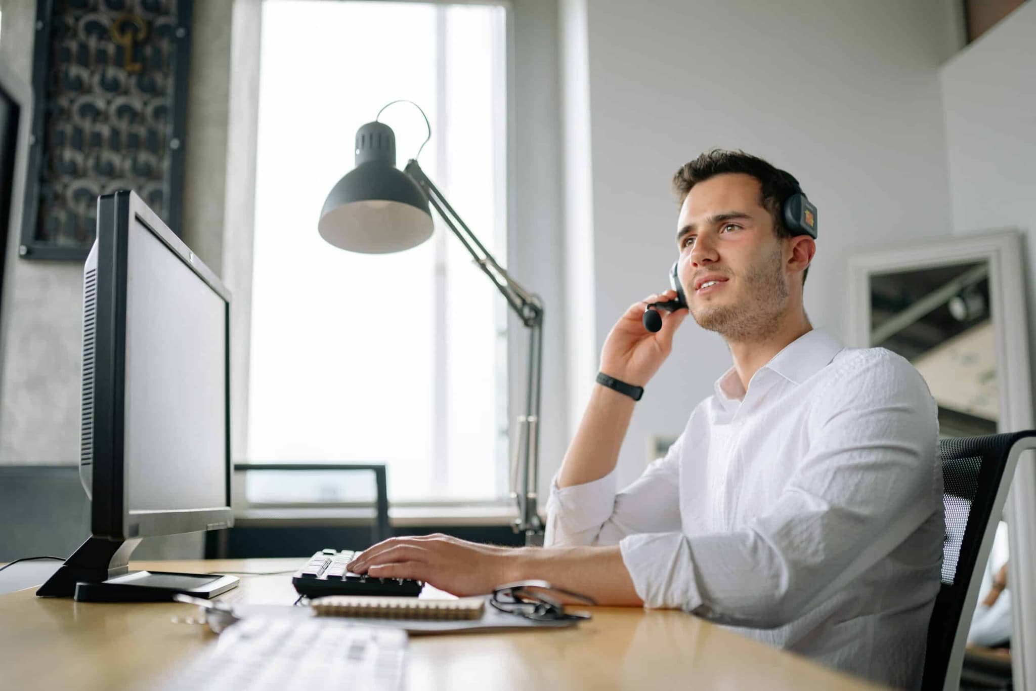 A person preparing for an interview is sitting in front of their monitor, holding their headset.