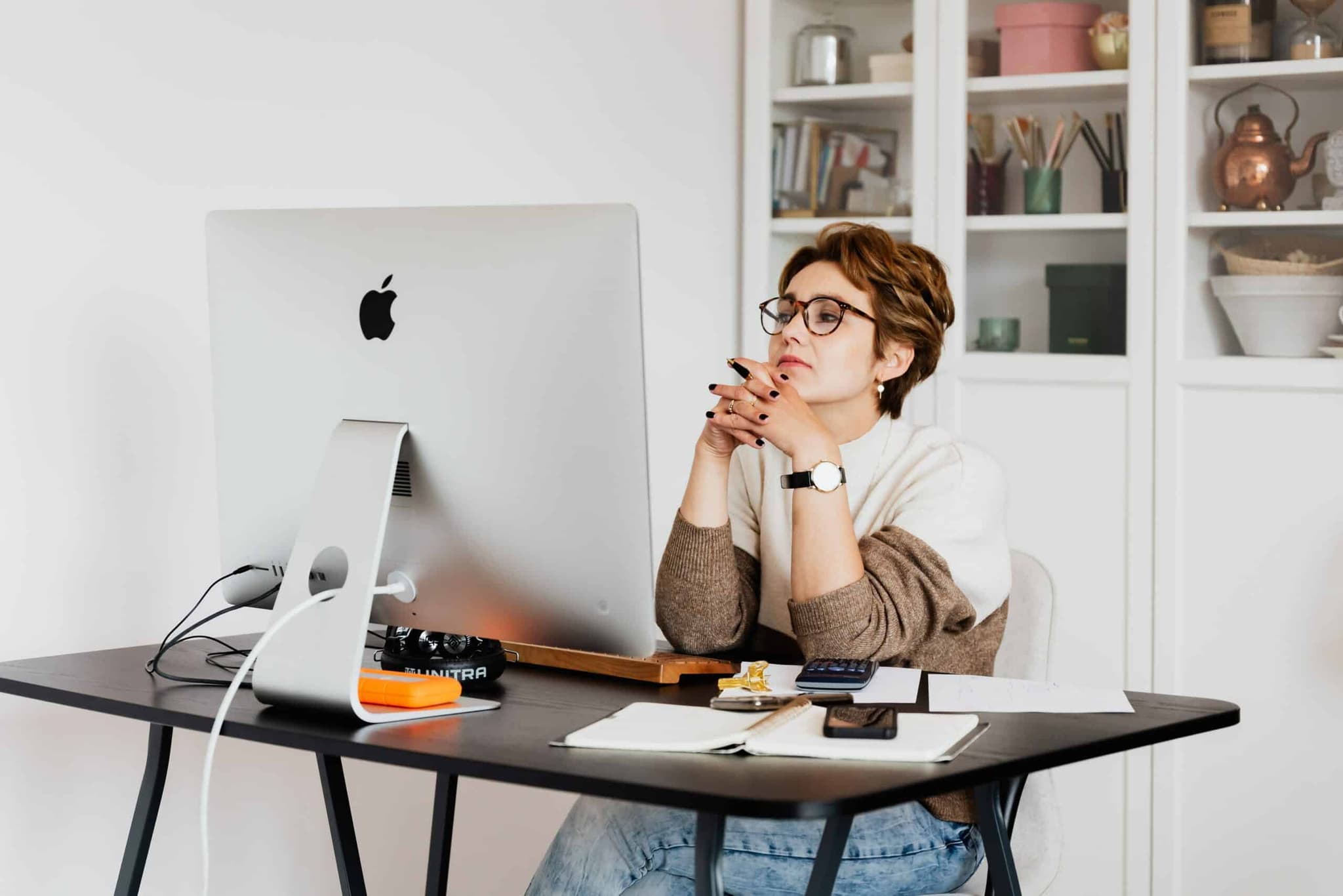 Girl sitting in a chair in front of a monitor, clutching her hand while deep in thought.